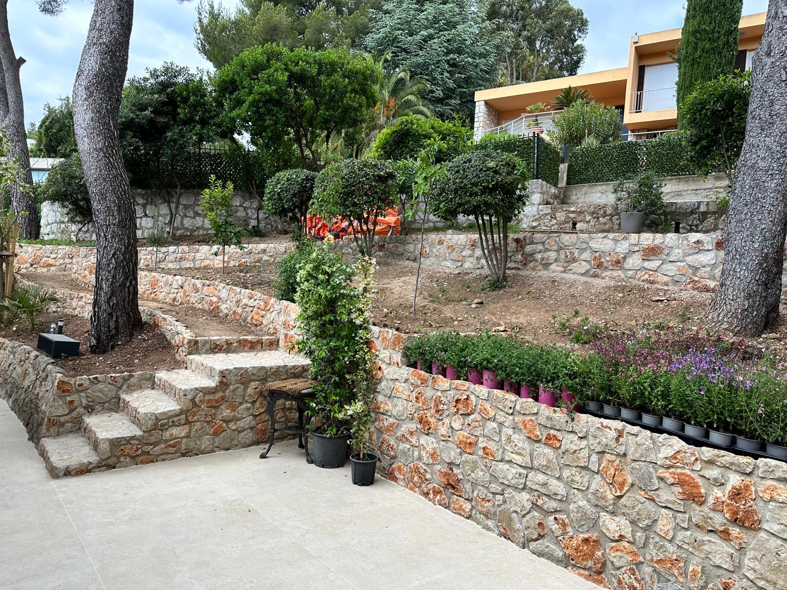 Giardino terrazzato con muretti a secco in pietra e paesaggio mediterraneo — lavori esterni di pregio