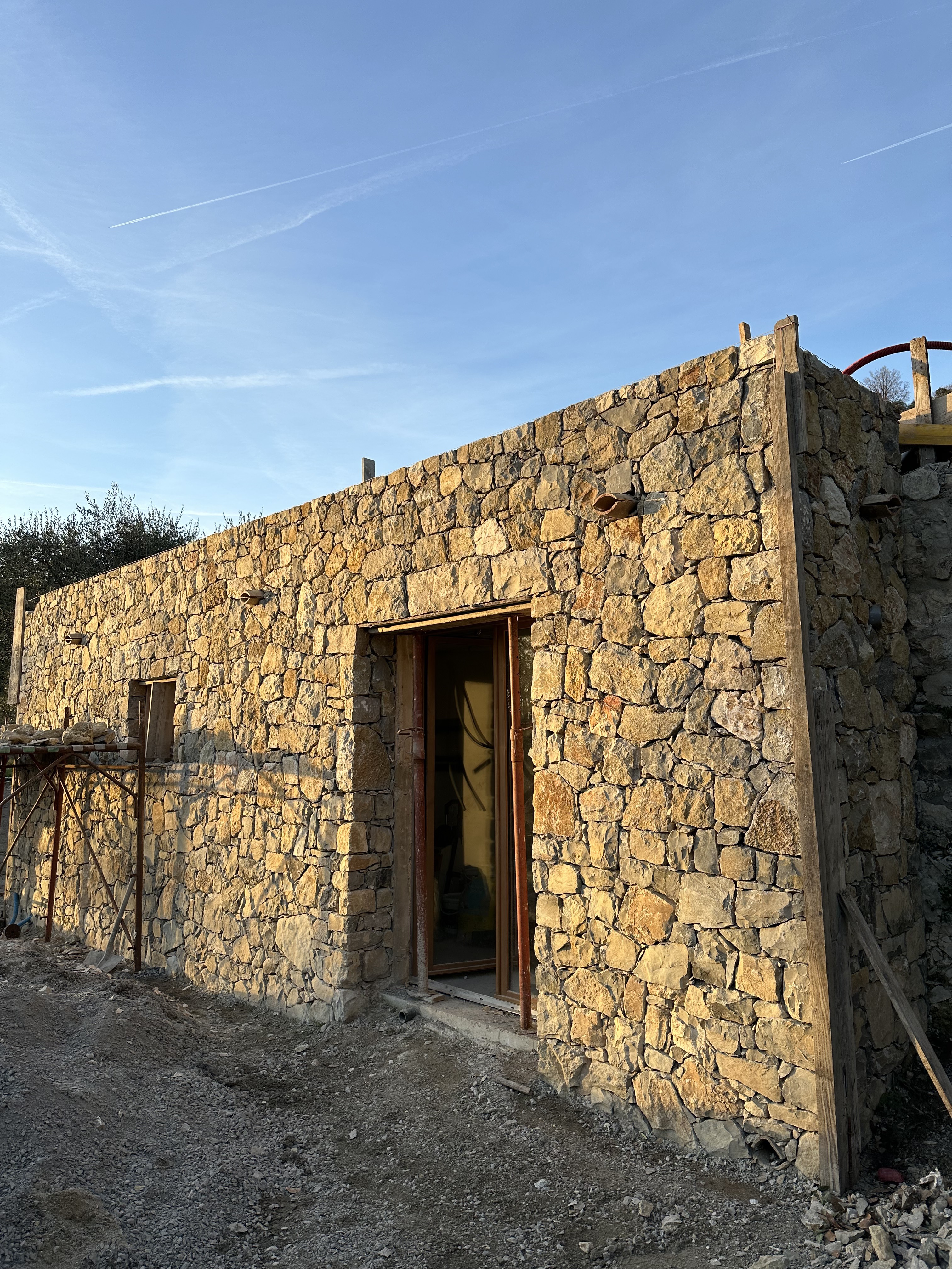 Edificio in costruzione con facciata in pietra naturale a secco — muratura tradizionale mediterranea